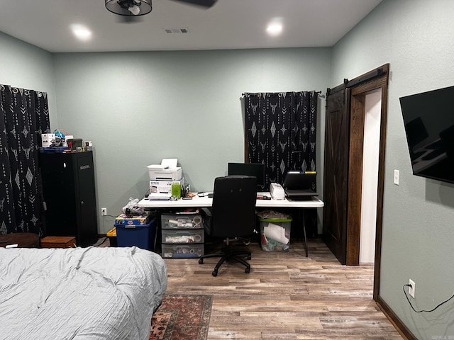 bedroom featuring a barn door and light hardwood / wood-style floors