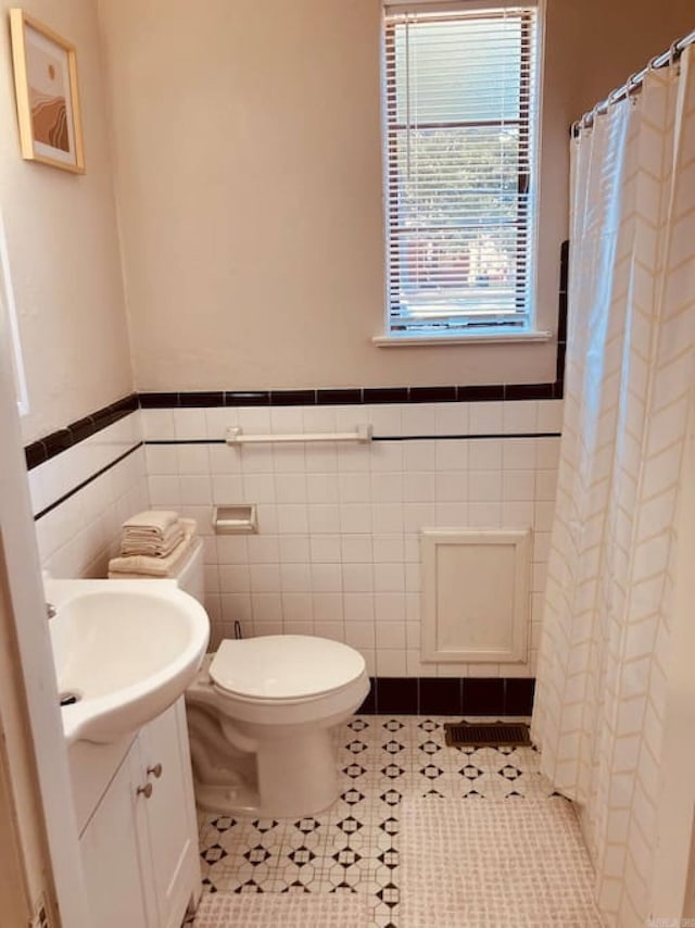 bathroom with tile patterned flooring, vanity, tile walls, and toilet