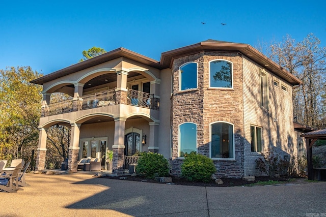 view of front facade with a balcony and french doors