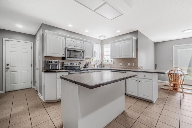 kitchen featuring a center island, tasteful backsplash, light tile patterned flooring, white cabinets, and appliances with stainless steel finishes