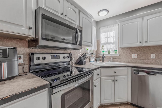 kitchen featuring white cabinets, light tile patterned floors, stainless steel appliances, and sink