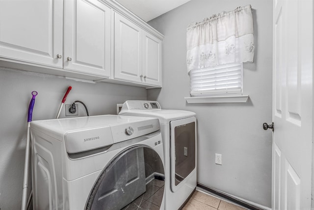 laundry area with washing machine and clothes dryer, light tile patterned flooring, and cabinets