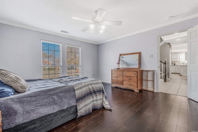 bedroom featuring hardwood / wood-style flooring, ensuite bath, ceiling fan, and crown molding