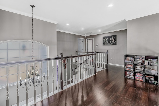 corridor with hardwood / wood-style floors, crown molding, and a notable chandelier