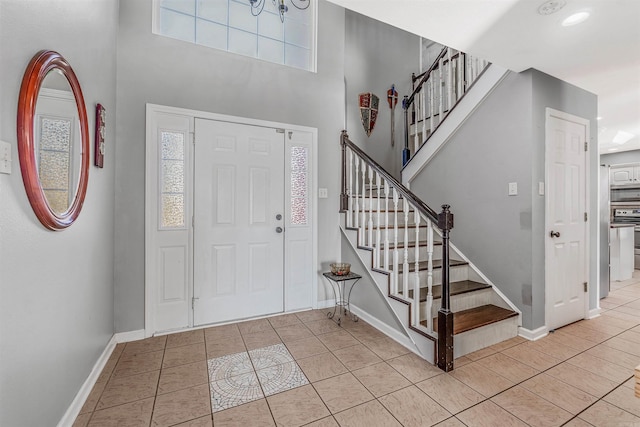 entryway with a towering ceiling and light tile patterned floors