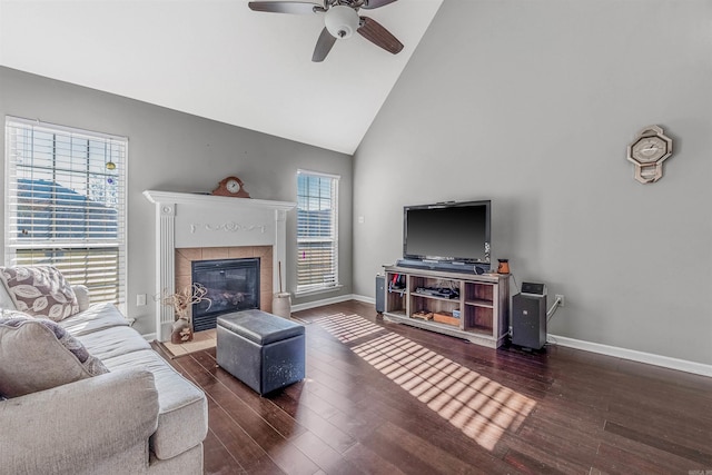 living room with ceiling fan, dark hardwood / wood-style flooring, high vaulted ceiling, and a tiled fireplace