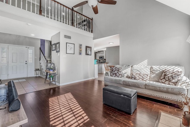 living room with ceiling fan, dark wood-type flooring, and a high ceiling