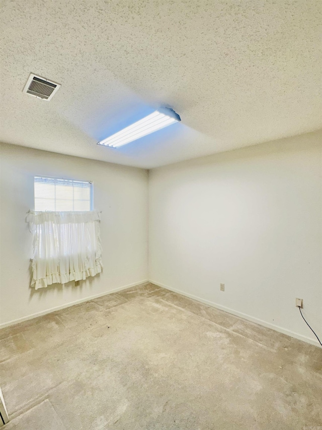 carpeted empty room with a textured ceiling