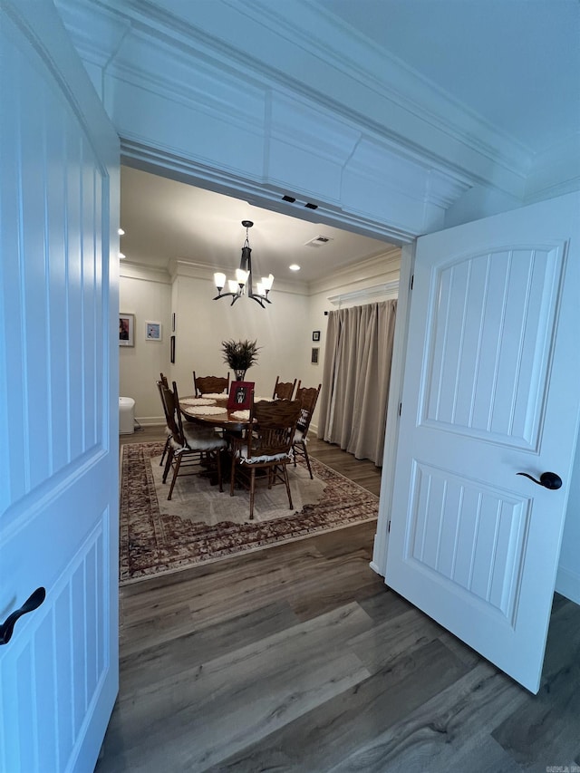 dining space with dark hardwood / wood-style flooring, an inviting chandelier, and ornamental molding