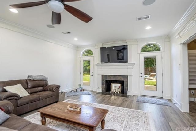 living room with a fireplace, ceiling fan, light wood-type flooring, and crown molding