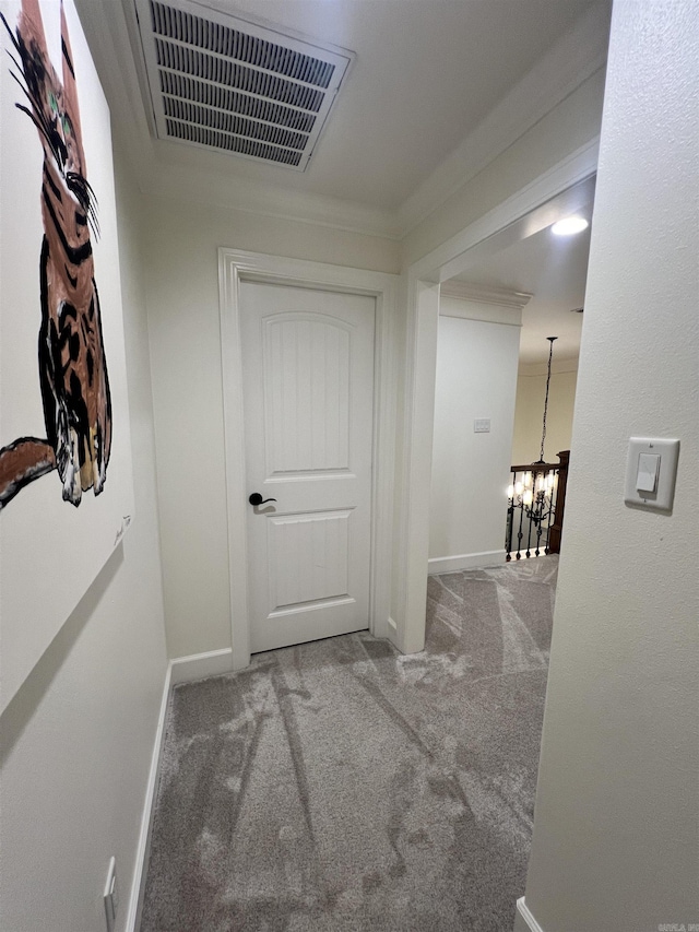 hallway featuring a notable chandelier and carpet floors