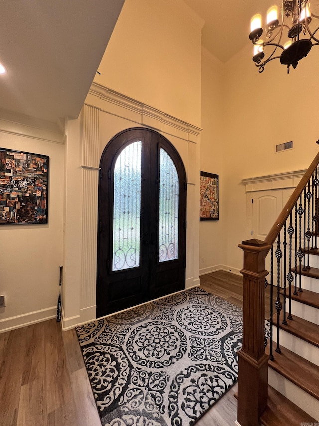 foyer featuring hardwood / wood-style floors, an inviting chandelier, a high ceiling, and french doors