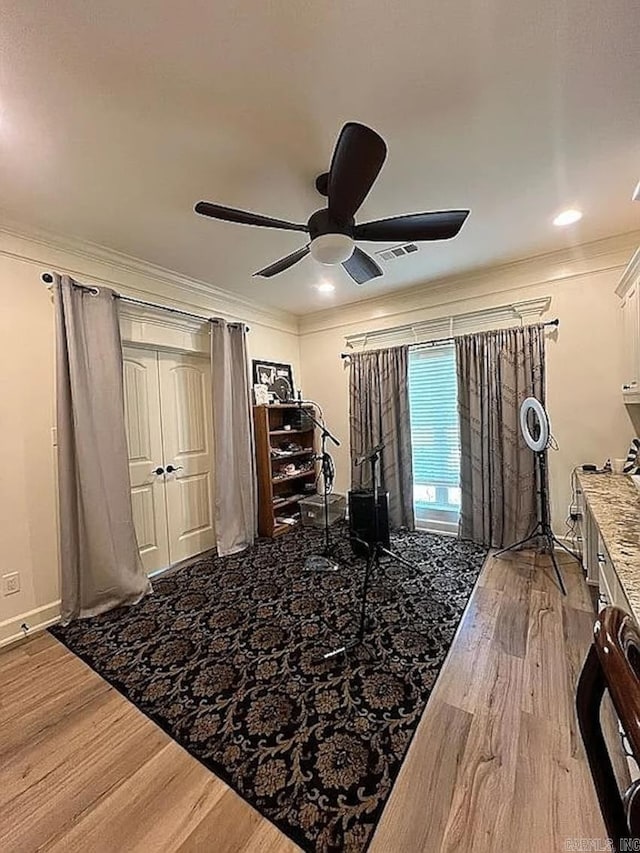 interior space with hardwood / wood-style flooring, ceiling fan, and ornamental molding