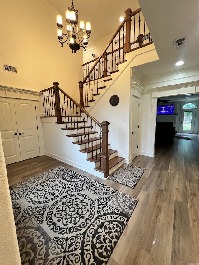 foyer featuring a chandelier, hardwood / wood-style flooring, and crown molding