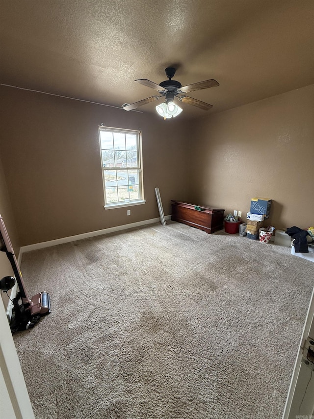 unfurnished bedroom featuring baseboards, ceiling fan, a textured ceiling, and carpet