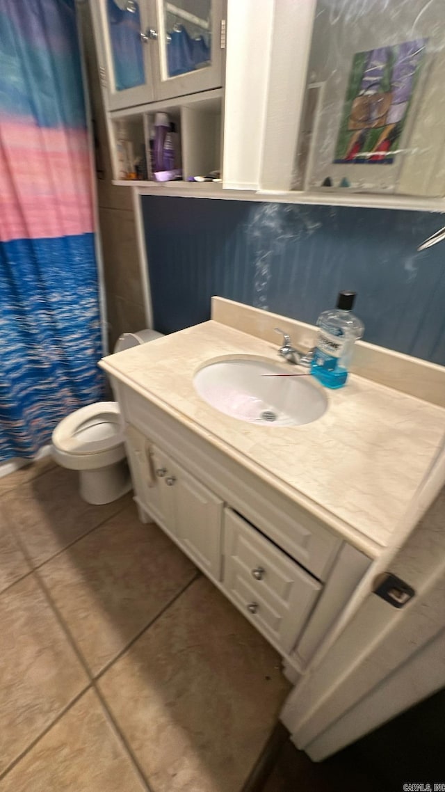 bathroom featuring tile patterned flooring, vanity, toilet, and walk in shower