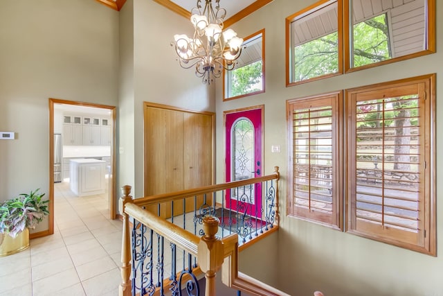 entrance foyer with light tile patterned floors, crown molding, a high ceiling, and a chandelier