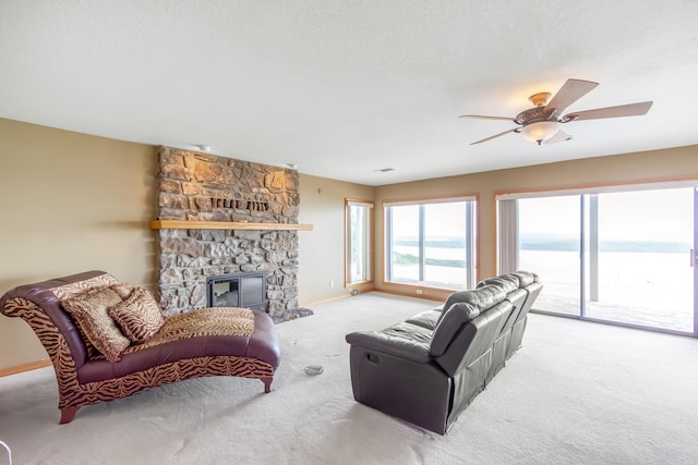 living room featuring ceiling fan, light colored carpet, a textured ceiling, a fireplace, and a water view