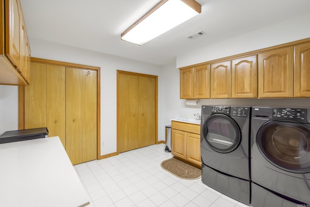 washroom with cabinets, sink, light tile patterned floors, and washer and dryer