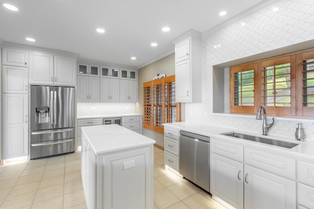 kitchen featuring appliances with stainless steel finishes, tasteful backsplash, sink, white cabinets, and a kitchen island