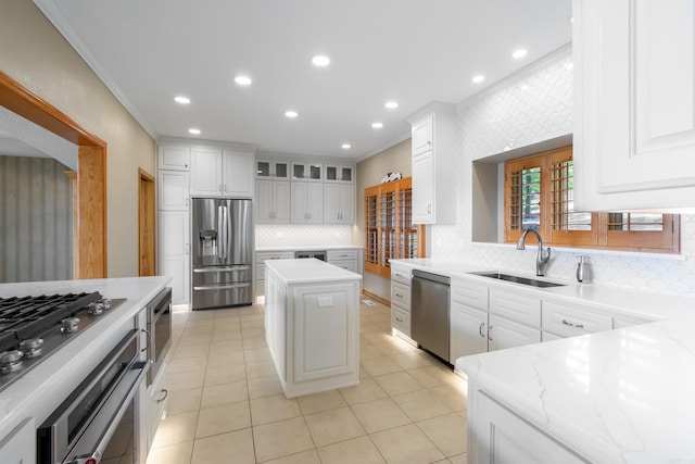 kitchen featuring sink, a center island, backsplash, white cabinets, and appliances with stainless steel finishes