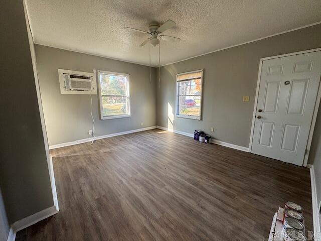 empty room featuring ceiling fan, dark hardwood / wood-style flooring, a textured ceiling, and a wall unit AC