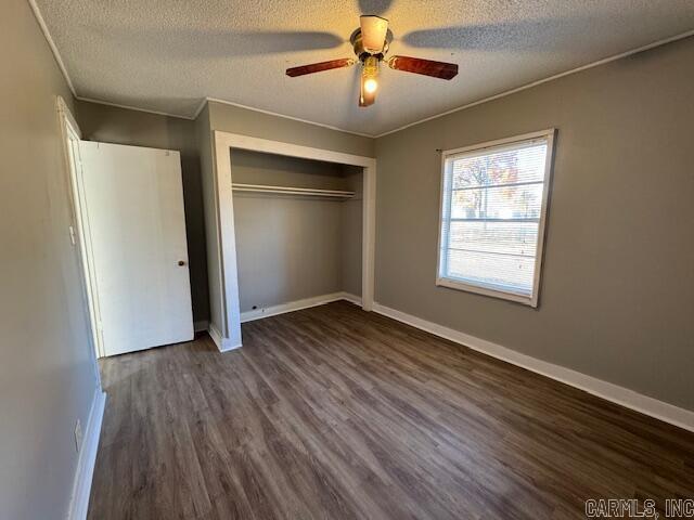 unfurnished bedroom featuring a textured ceiling, dark hardwood / wood-style flooring, a closet, and ceiling fan