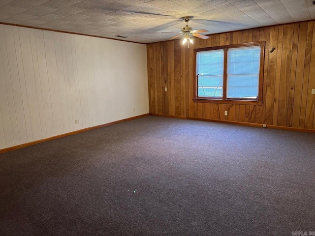 empty room featuring wood walls, carpet, and ceiling fan