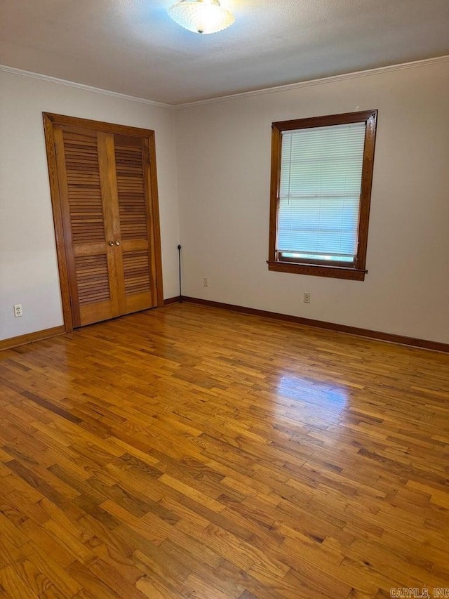 unfurnished bedroom with light hardwood / wood-style floors, a closet, and crown molding