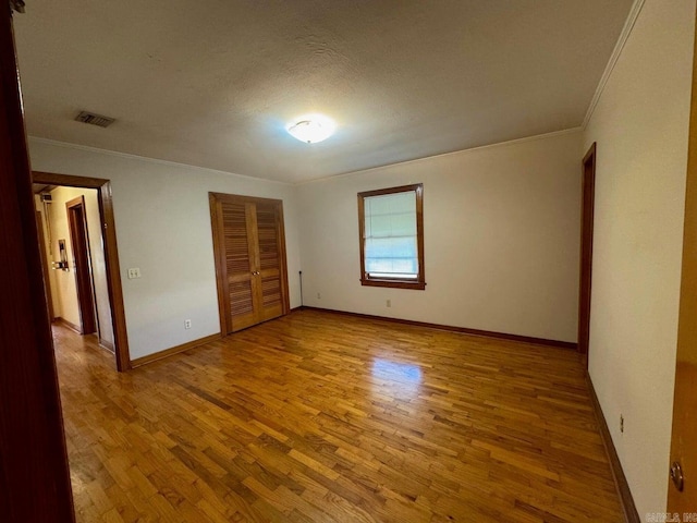 unfurnished bedroom with a textured ceiling, light hardwood / wood-style flooring, a closet, and ornamental molding