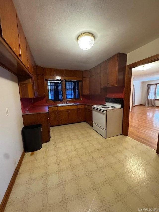 kitchen with a textured ceiling, light hardwood / wood-style flooring, white range with electric stovetop, and sink