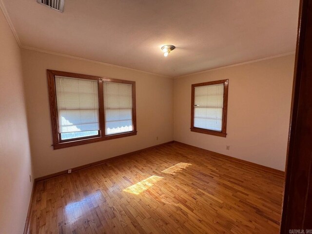 unfurnished room with a wealth of natural light, light hardwood / wood-style floors, and ornamental molding