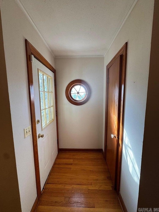 doorway featuring hardwood / wood-style flooring, ornamental molding, and a textured ceiling