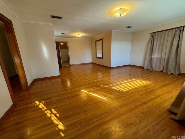 spare room featuring a textured ceiling, wood-type flooring, and ornamental molding