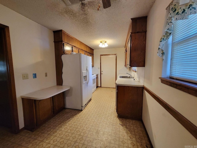 kitchen featuring a textured ceiling, white appliances, and sink