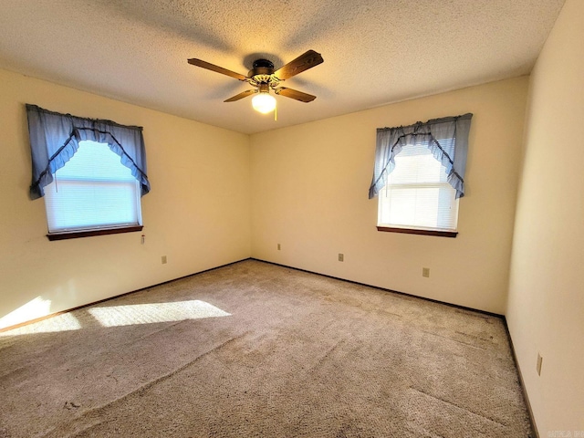 carpeted spare room featuring plenty of natural light, ceiling fan, and a textured ceiling