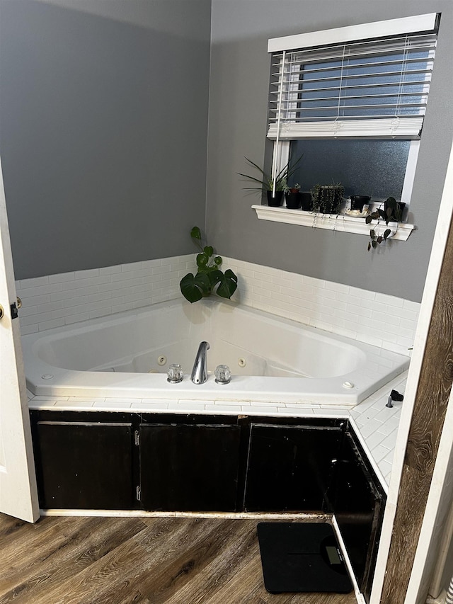 bathroom with hardwood / wood-style floors and a tub to relax in