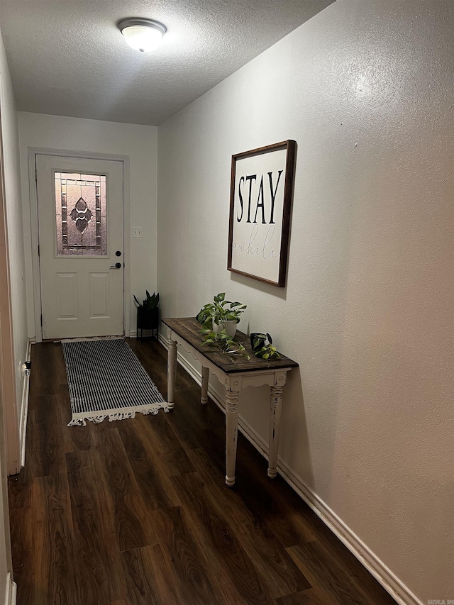 doorway with a textured ceiling and dark hardwood / wood-style floors