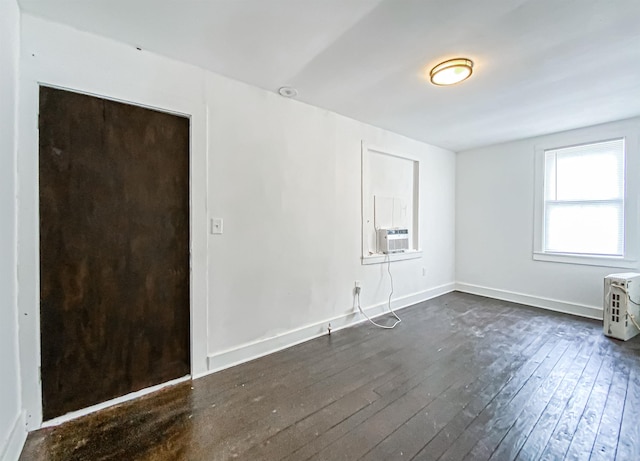 empty room featuring cooling unit and dark wood-type flooring