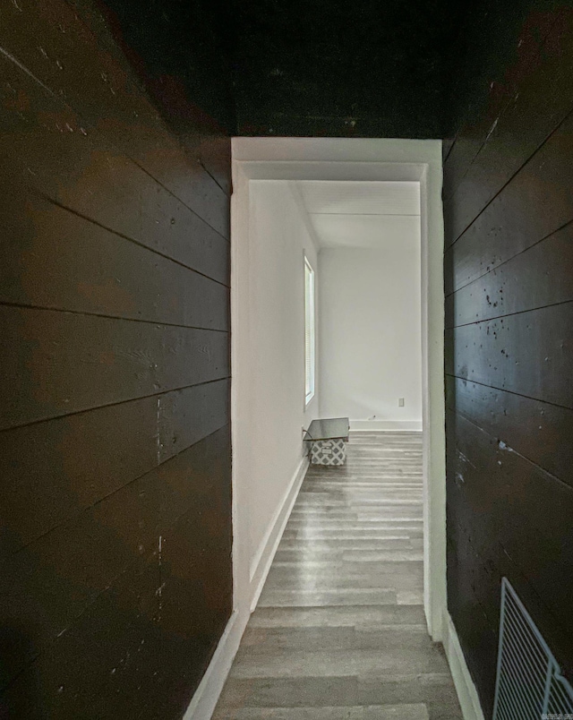 hall with hardwood / wood-style floors and wooden walls