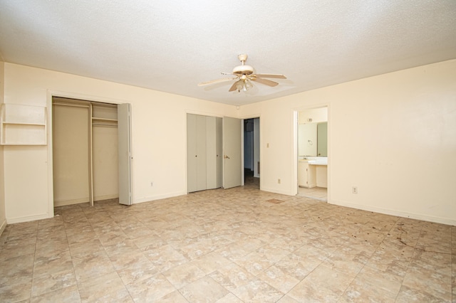 unfurnished bedroom with ceiling fan, ensuite bathroom, and a textured ceiling