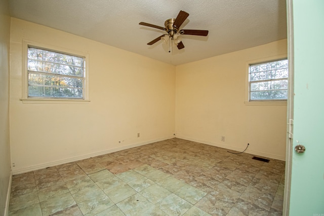 spare room featuring a textured ceiling, ceiling fan, and a healthy amount of sunlight