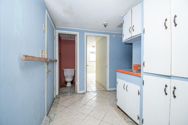 kitchen featuring white cabinets, a textured ceiling, light tile patterned flooring, and sink