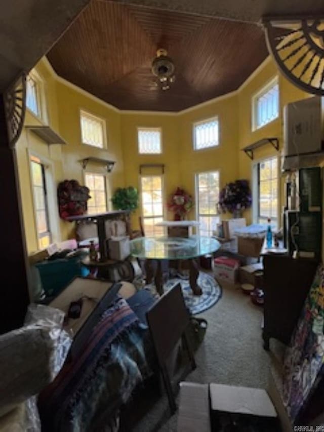 carpeted living room featuring ceiling fan, wood ceiling, a high ceiling, and ornamental molding