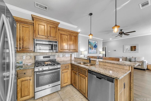 kitchen featuring hanging light fixtures, sink, ornamental molding, appliances with stainless steel finishes, and kitchen peninsula