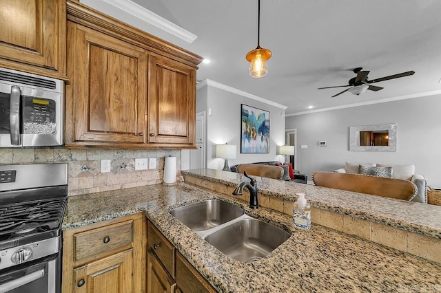 kitchen featuring sink, ornamental molding, appliances with stainless steel finishes, tasteful backsplash, and decorative light fixtures