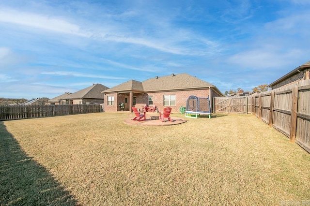 back of property with a yard, a trampoline, and a patio area