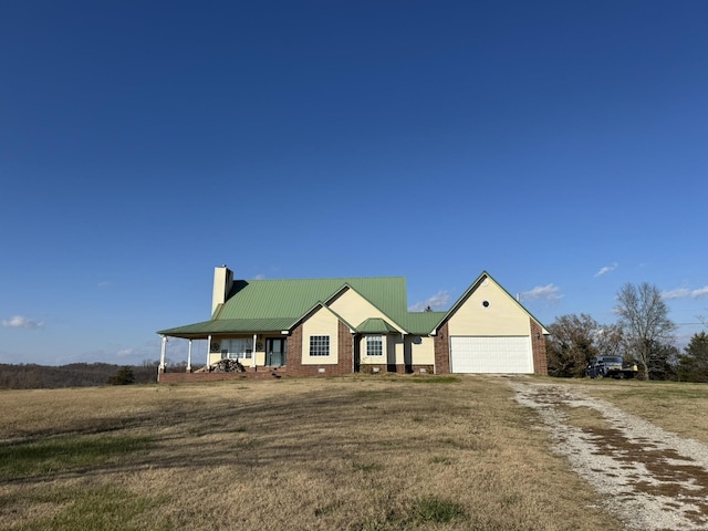 view of front of home featuring covered porch, a garage, and a front lawn