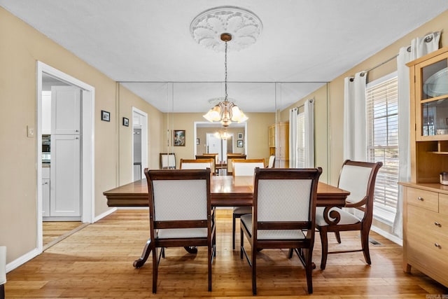 dining space featuring light hardwood / wood-style flooring and a notable chandelier