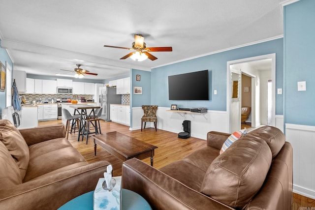 living room with light hardwood / wood-style flooring, ceiling fan, and ornamental molding